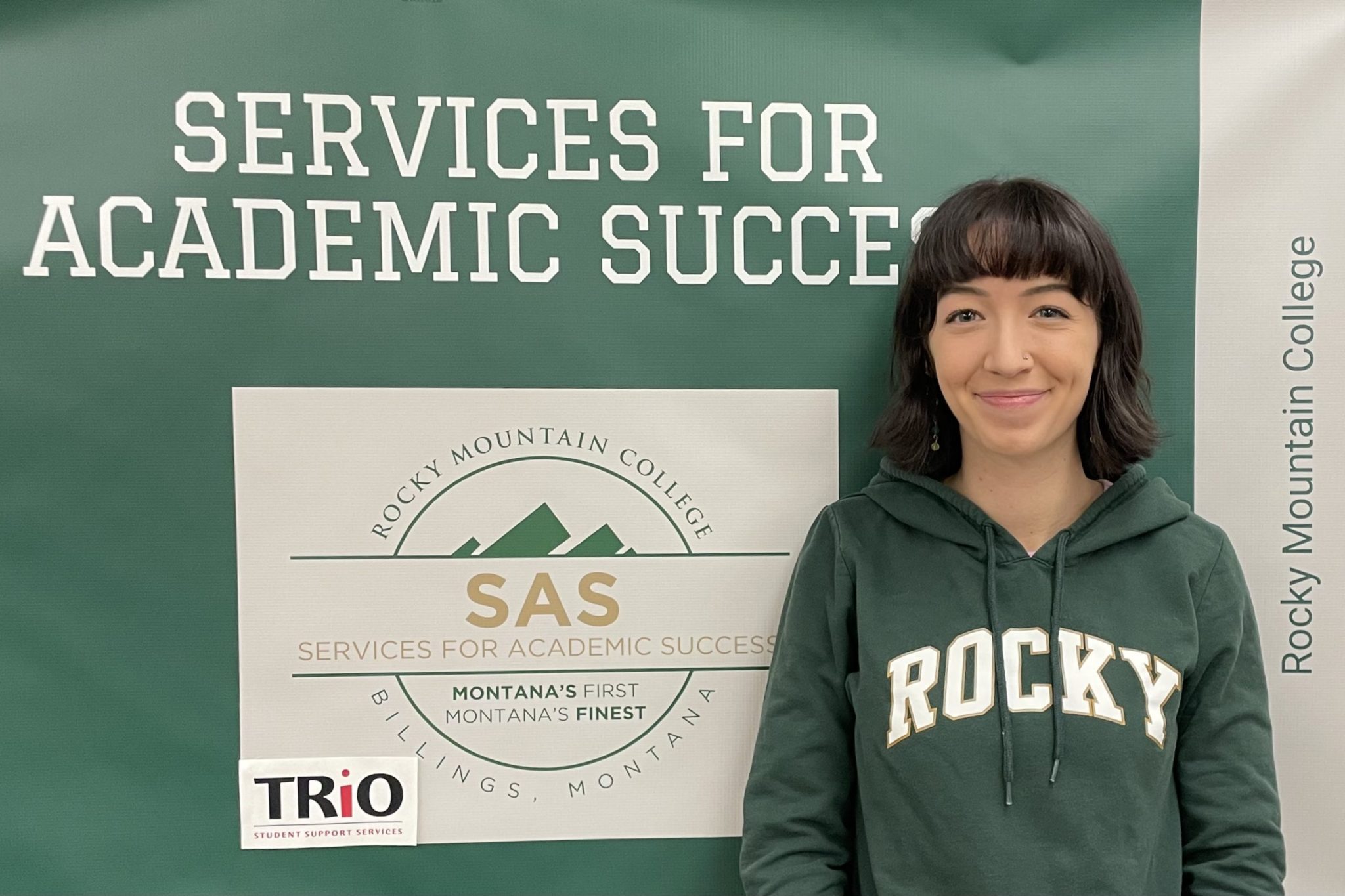 Student Caitlin Kenney standing in front of Services of Academic Success (SAS) sign.